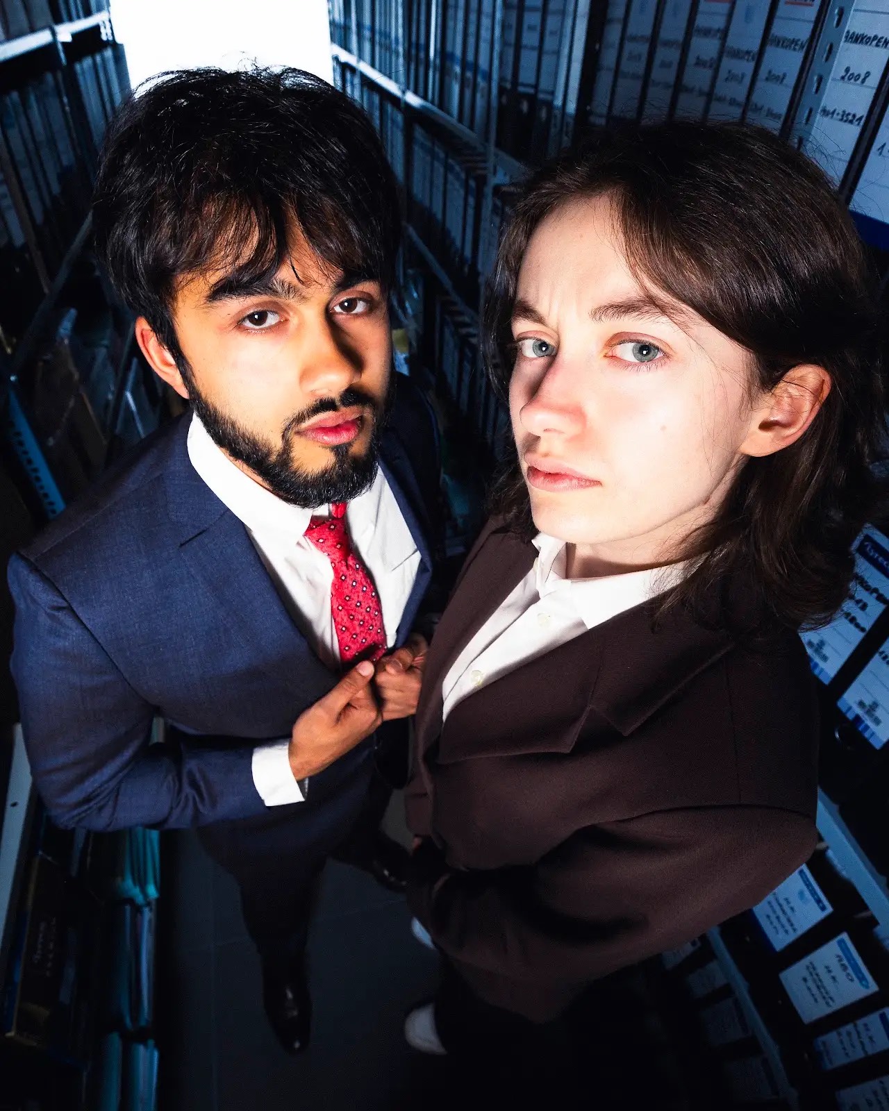 Een man en een vrouw in pak tussen archiefrekken